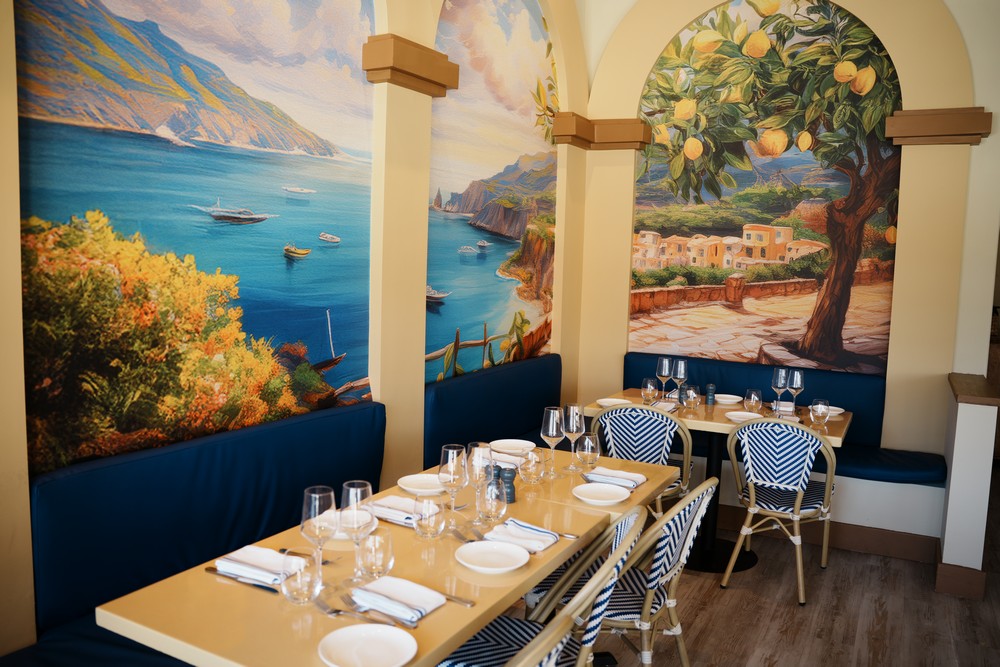 Long communal table beneath the Amalfi mural at Amuri